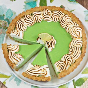 Top view of a Toasted Coconut Lime Meringue Tart with a few slices cut into it.