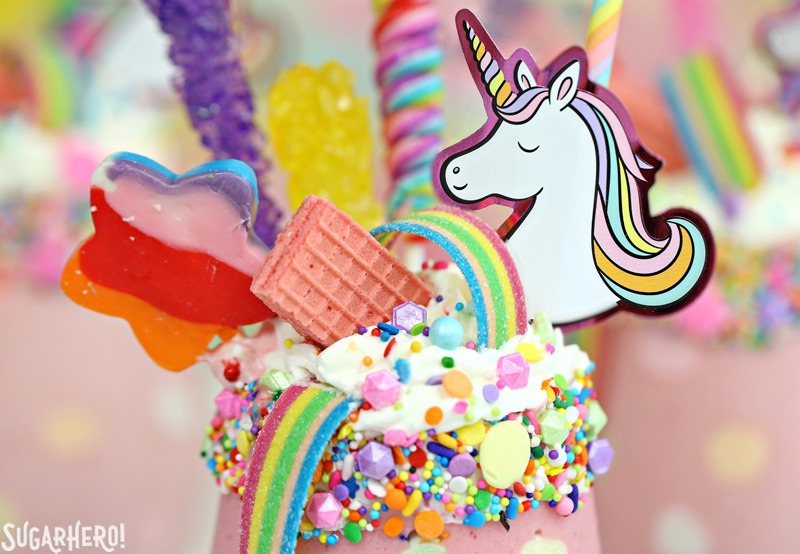 Unicorn Milkshakes - strawberry milkshakes decorated with sprinkles, cookies, lollipops, and rainbow candies. | From SugarHero.com
