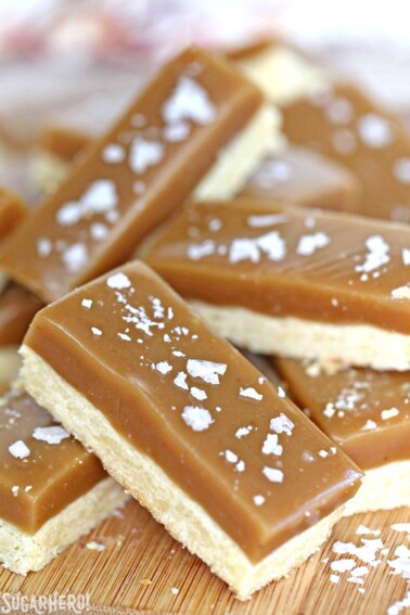 Salted Caramel Bars stacked haphazardly on a wooden surface.