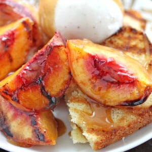 Close up of Grilled Pound Cake and Peaches on a white plate with a scoop of ice cream.