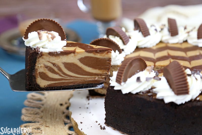 Chocolate Peanut Butter Cheesecake - this is the ULTIMATE cheesecake! Smooth and creamy, with gorgeous chocolate swirls and lots of peanut butter cups! | From SugarHero.com Chocolate Peanut Butter Cheesecake - removing a slice from the whole cake | From SugarHero.com