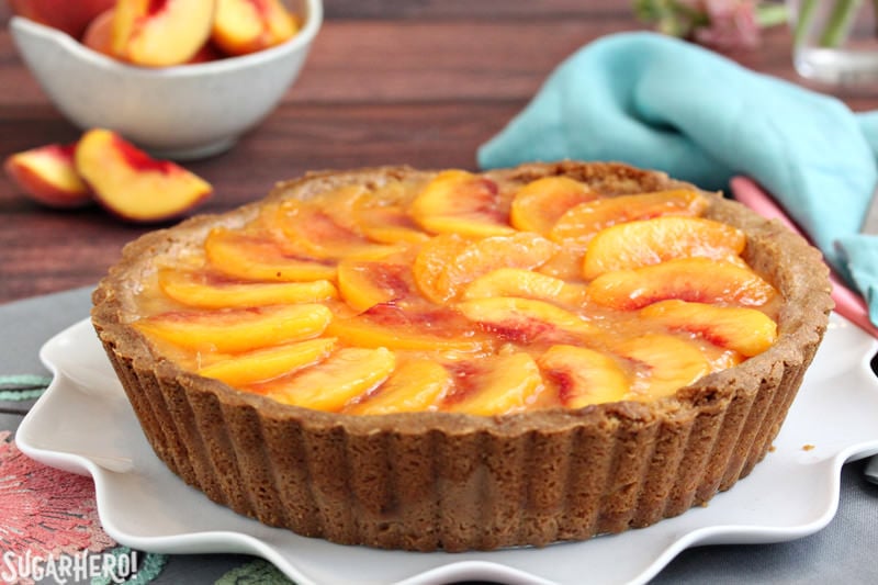 Fresh Peach Tart - the BEST way to enjoy peaches! No-bake tart recipe featuring juicy ripe peaches in a buttery shell | From SugarHero.com A whole no-bake Fresh Peach Tart on a serving plate | From SugarHero.com