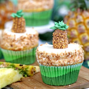 Close up of a Pineapple Cupcake on a cutting board next to sliced pineapple.
