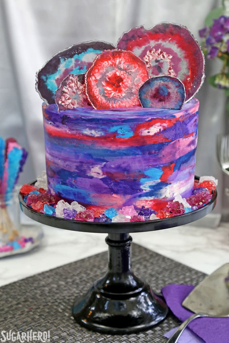 Agate Cake - with gorgeous, EDIBLE candy agate slices, and a pretty watercolor buttercream effect! | From SugarHero.com Agate Cake - purple, blue, and pink watercolor cake with edible candy agate slices on top | From SugarHero.com