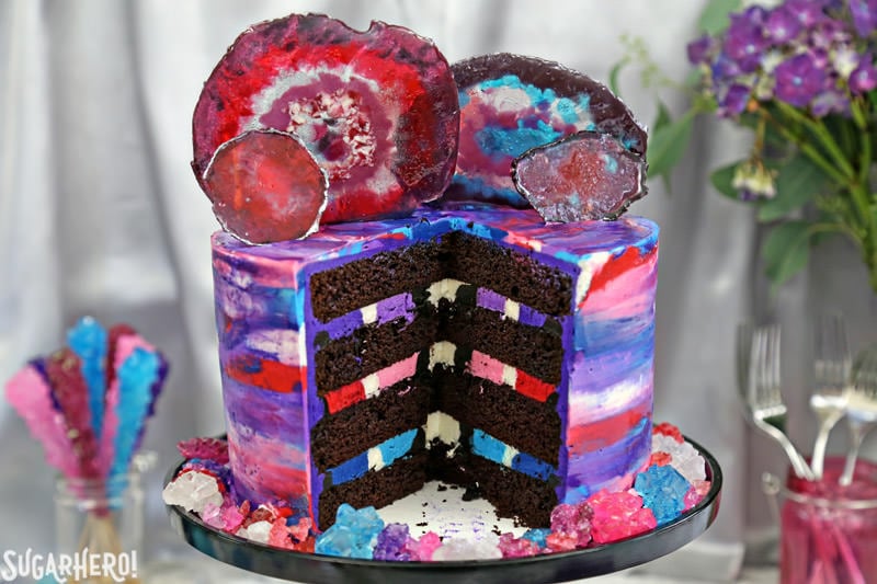 Agate Cake - with gorgeous, EDIBLE candy agate slices, and a pretty watercolor buttercream effect! | From SugarHero.com Agate Cake, sliced into to show the chocolate cake interior and striped multi-colored buttercream filling | From SugarHero.com