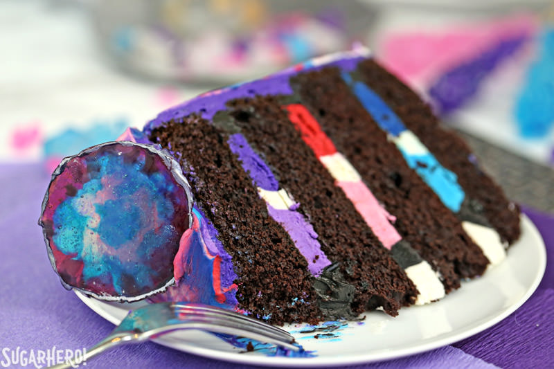 Slice of Agate Cake - moist chocolate cake with multi-colored buttercream filling and a candy agate slice on top | From SugarHero.com