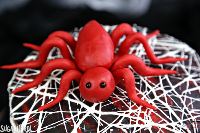 Red Velvet Marshmallow Spiderweb Cake - close-up of red candy spider on top of cake | From SugarHero.com