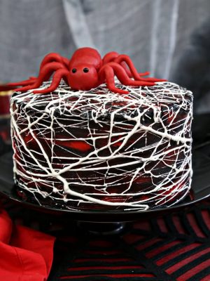 Close up of Red Velvet Marshmallow Spiderweb Cake on a black cake stand.