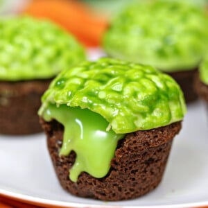 Close up of oozing Zombie Brain Brownie Bite on a plate with several more brownie bites in the background.