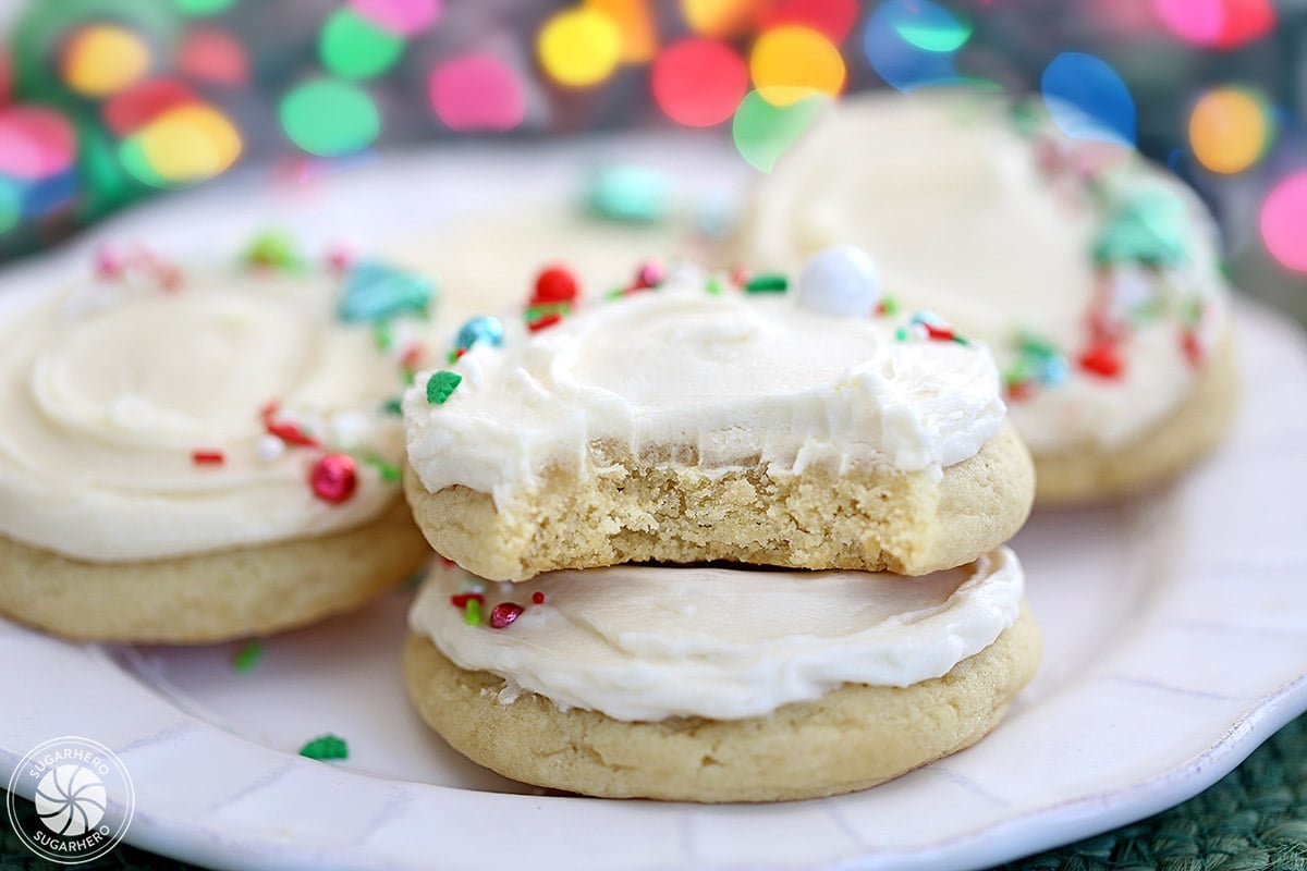 Big Soft Sugar Cookies - sugar cookies on a plate, with vanilla frosting and holiday sprinkles on top | From SugarHero.com