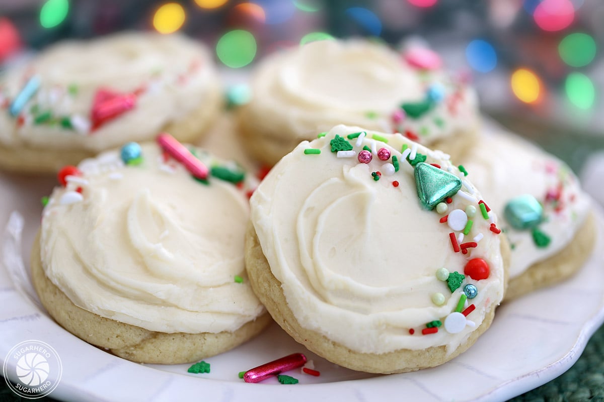 Six big soft sugar cookies on a white plate with scalloped edges.