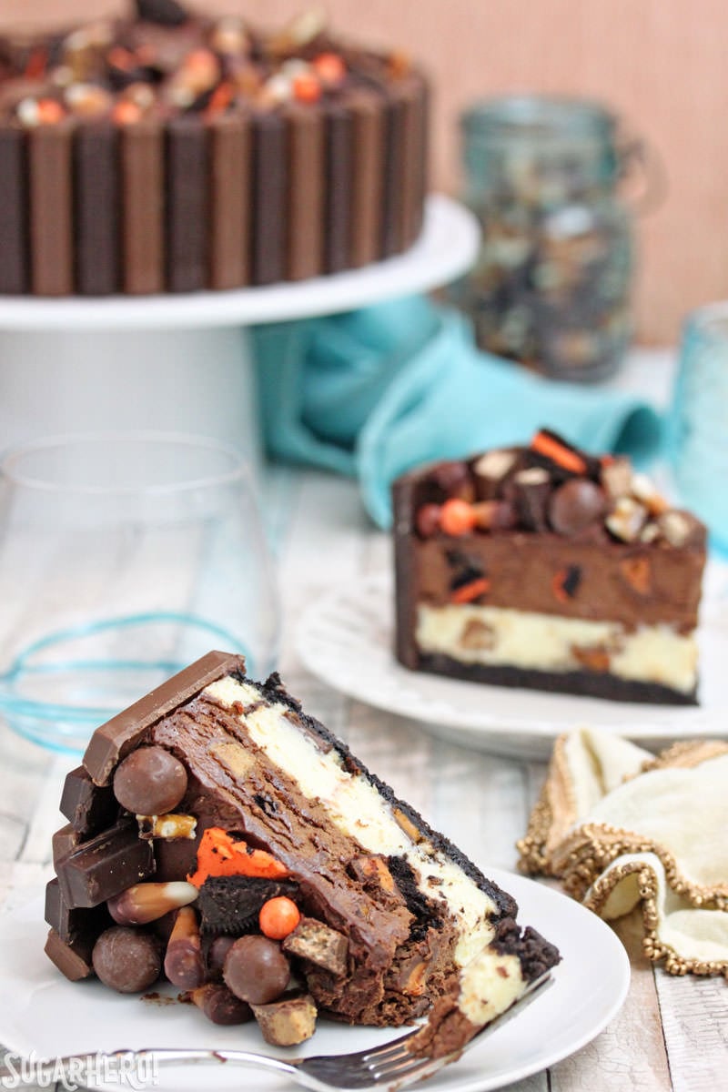 Candy Bar Cheesecake – a creamy chocolate-vanilla cheesecake PACKED with candy bars! It’s a great way to use up extra candy! | From SugarHero.com Candy Bar Cheesecake – two cake slices, one with a bite taken out of it | From SugarHero.com