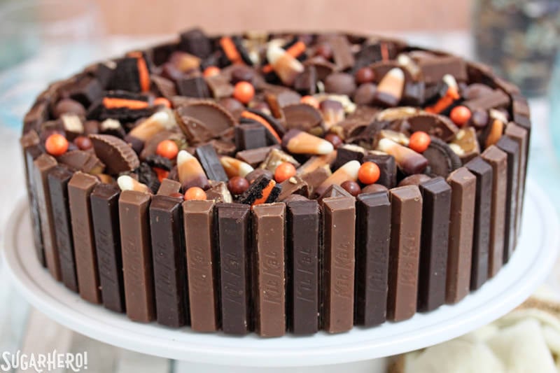 Candy Bar Cheesecake – a chocolate-vanilla cheesecake made with candy and ringed with Kit Kat bars | From SugarHero.com