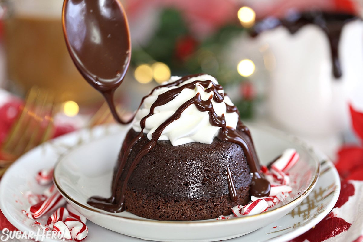 Peppermint Mocha Lava Cakes - spoon drizzling chocolate sauce on top of a lava cake | From SugarHero.com