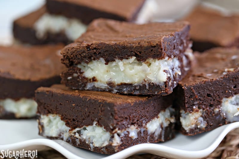These are the BEST Coconut Brownies! Rich, fudgy brownies and a gooey coconut center. Better than a candy bar! | From SugarHero.com The BEST Coconut Brownies - close-up of gooey coconut brownies on a plate | From SugarHero.com