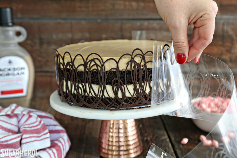 Peppermint Mocha Mousse Cake - pulling off an acetate cake collar from the side of the cake to reveal the mousse cake underneath | From SugarHero.com