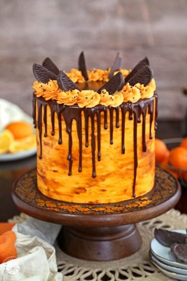 Chocolate Orange Cake on a wooden cake stand in front of a wooden background.