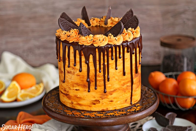 Chocolate Orange Cake on a wooden cake stand in front of a wooden background