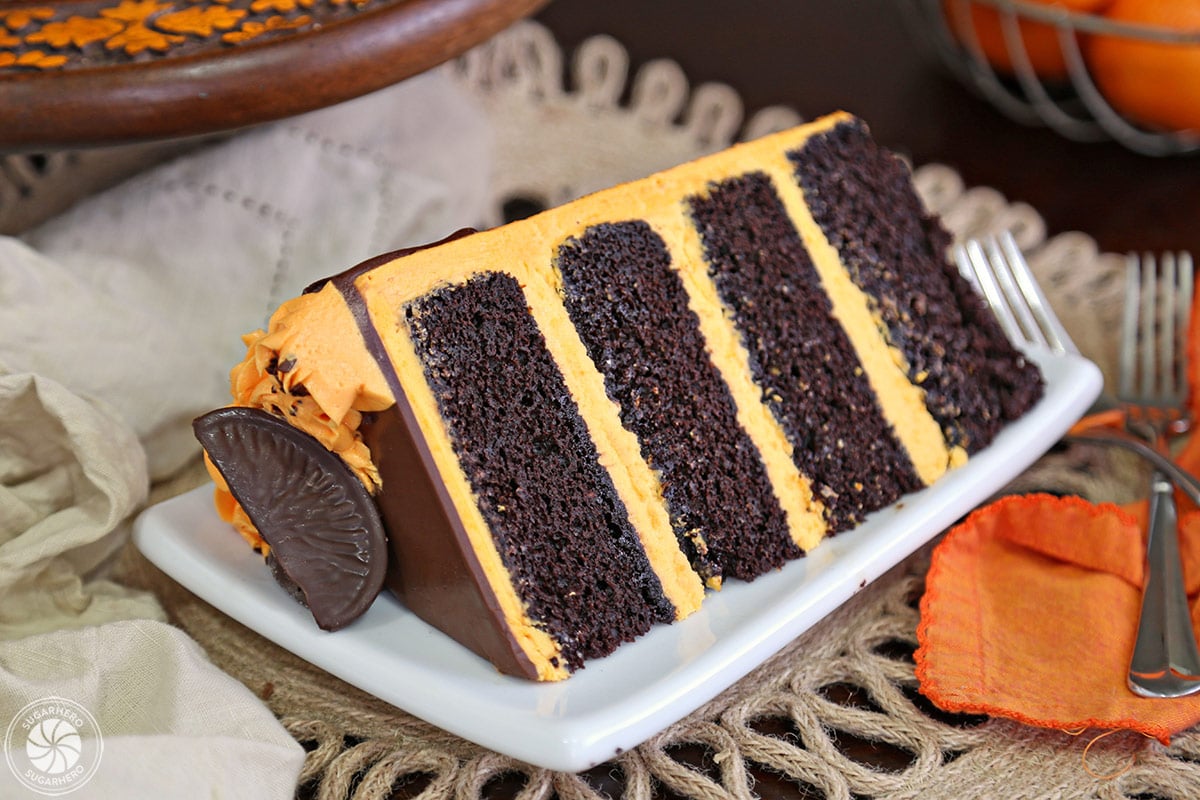 Chocolate-Orange Cake - If you love chocolate-orange flavors, this cake is for you! It's a delicious chocolate cake filled with tangy orange buttercream and topped with chocolate oranges. | From SugarHero.com close-up of an individual cake slice