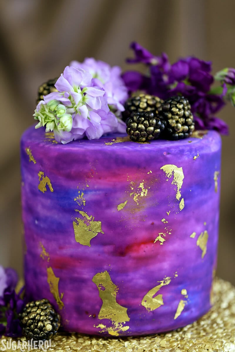 Gold Sequin Watercolor Cake - a stunning layer cake decorated with completely edible gold sequins and a gorgeous watercolor fondant effect! Perfect for parties, showers, or as a nontraditional wedding cake! | From SugarHero.com Gold Sequin Watercolor Cake - close-up of watercolor cake layer | From SugarHero.com