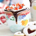 A mug of Strawberry Hot Chocolate next to cookies.