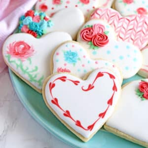 Close up of a heart-shaped cookie decorated with royal icing rosettes.
