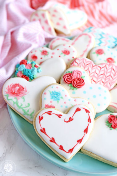 A blue plate filled with Valentine's Day Sugar Cookies.