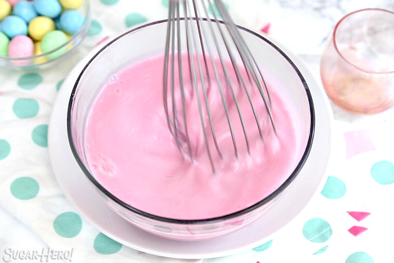 Action shot whisking a pink bowl of gelatin.