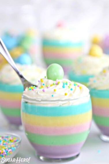 Pastel rainbow gelatin cup with a spoon sticking out of the top.