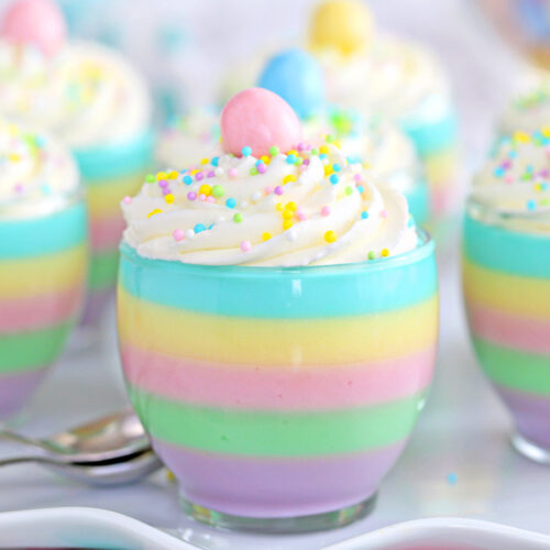 Close up of a pastel rainbow gelatin cup with 6 other cups in the background.