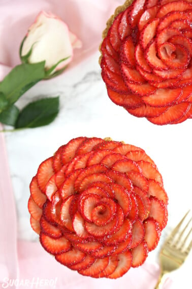 Overhead shot of two Strawberry Rose Tarts on a marble surface.
