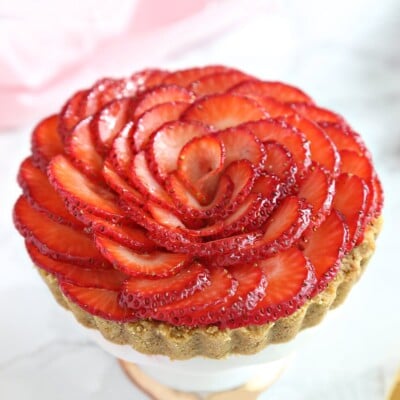 Close-up of a mini tart with a strawberry rose decoration on top.