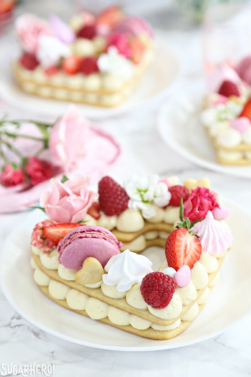 Trendy Cream Tarts - close-up shot of a cream biscuit with meringues, macarons, berries, and more on top | From SugarHero.com