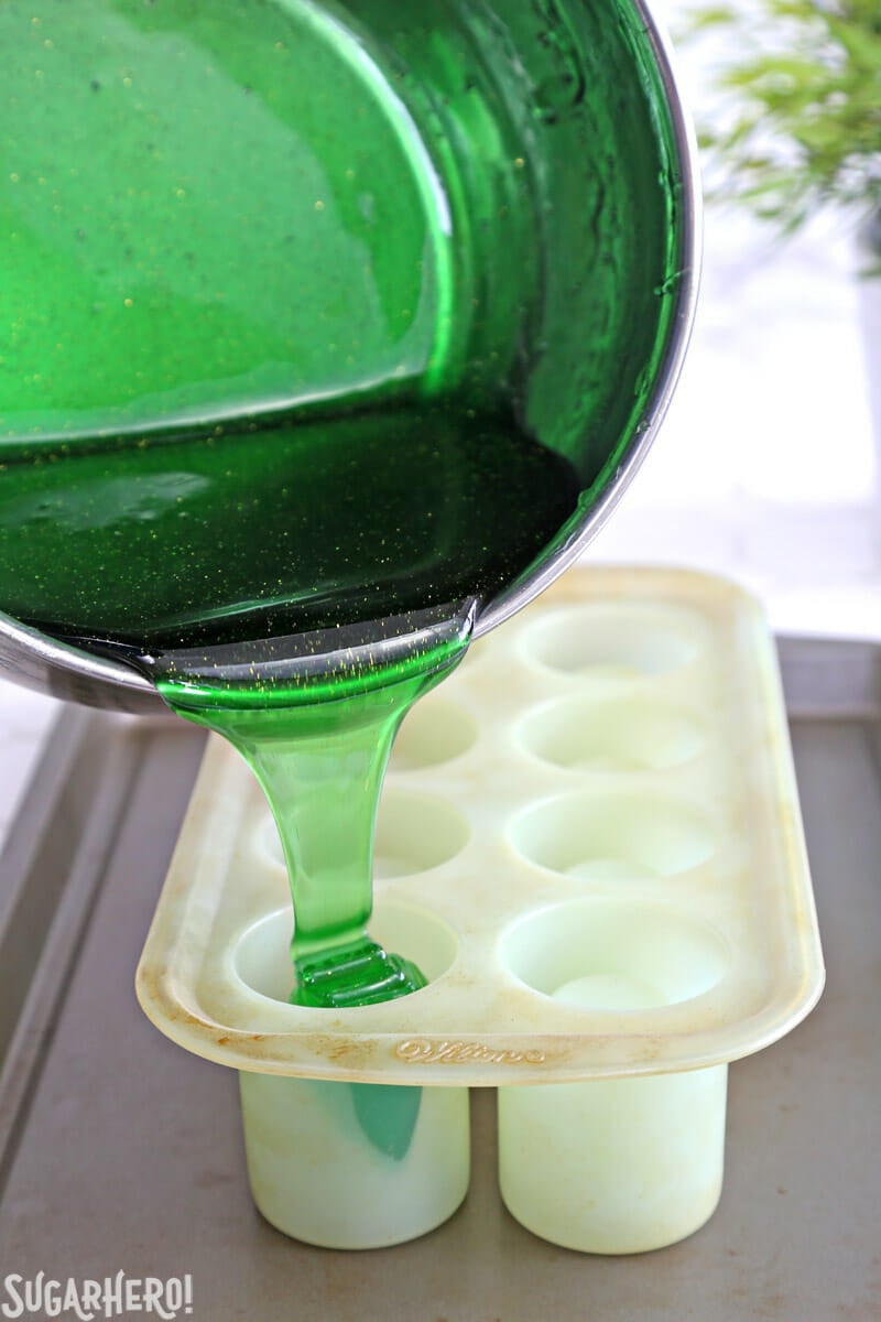 DIY Candy Shot Glasses - saucepan pouring hot sugar syrup into shot glass mold | From SugarHero.com