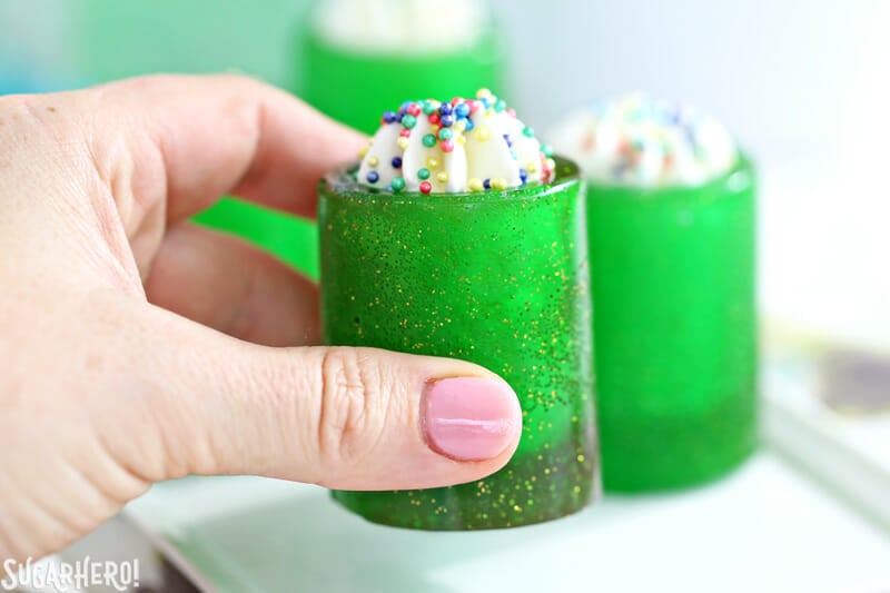 DIY Candy Shot Glasses - raising a candy glass filled with whipped cream and sprinkles | From SugarHero.com