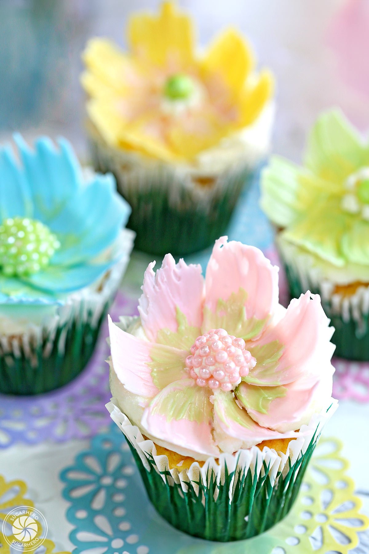 Four chocolate flower cupcakes on colorful doilies.