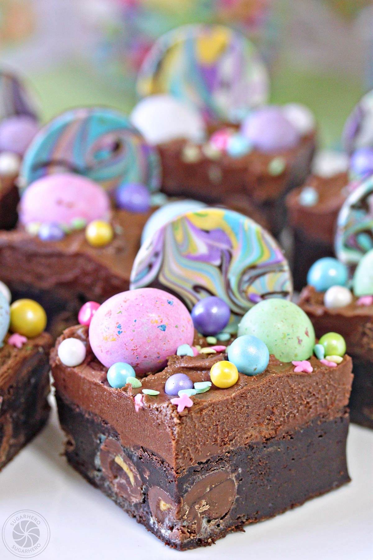 Malted Milk Chocolate Brownies - ultra-fudgy brownies, packed with malted candies and topped with chocolate frosting and LOTS of fun sprinkles and candies! They're perfect for Easter, showers, and birthday parties. | From SugarHero.com Malted Milk Chocolate Brownies -close-up of brownies with colorful sprinkles and candies on top | From SugarHero.com