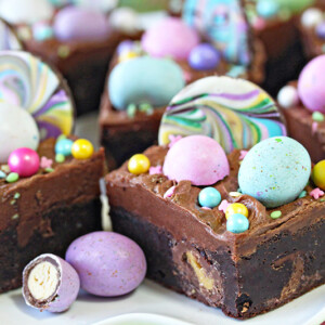Eight Frosted Easter Brownies covered in chocolate frosting and topped with chocolate eggs and sprinkles.
