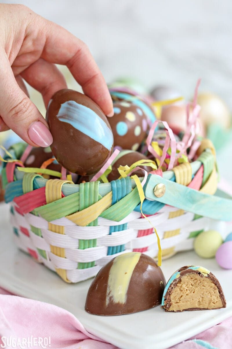 Hand taking a Peanut Butter Easter Egg out of a pastel Easter basket