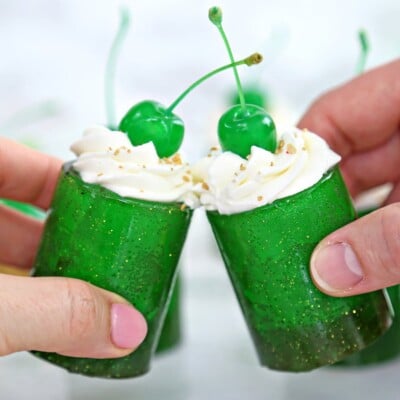 Two hands making a toast with Shamrock Shake Shots.