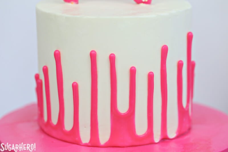 Circus Animal Layer Cake - a big, bright pink cake with funfetti cake layers, chopped up circus animal cookies inside, and a cool upside-down ganache drip decoration! | From SugarHero.com Circus Animal Layer Cake - close-up of upside-down pink ganache drip on circus animal cake | From SugarHero.com