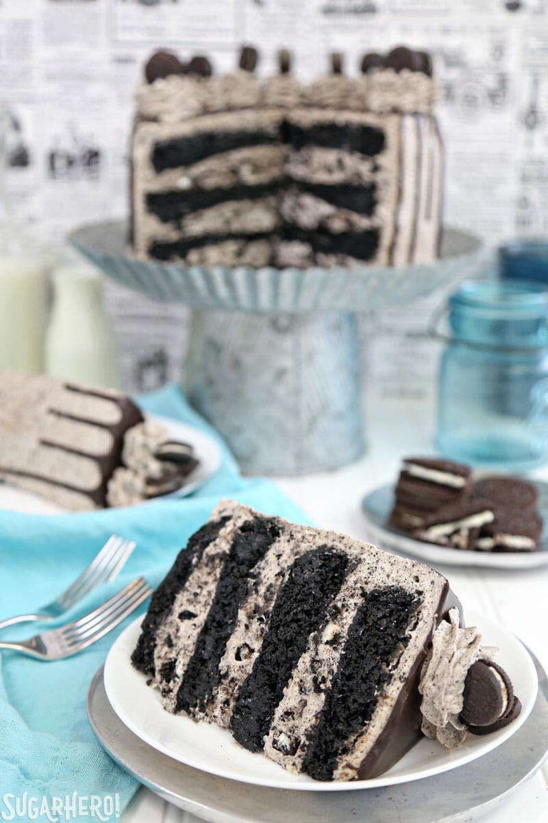 Cookies and Cream Cake - close-up of cake slice, with cake on cake stand in the background | From SugarHero.com