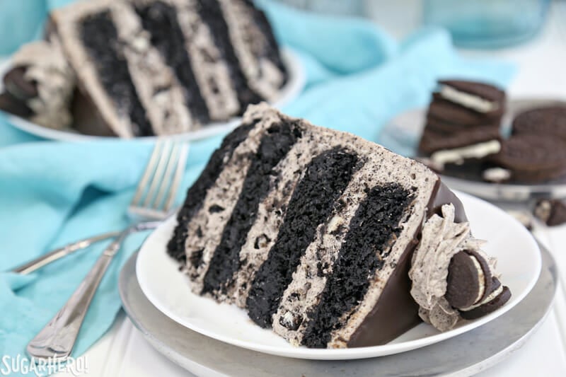 Cookies and Cream Cake - this epic cookies and cream layer cake will satisfy ALL of your chocolate cravings! It has rich devil's food cake plus buttercream with lots of cookie crumbs mixed right in. | From SugarHero.com Cookies and Cream Cake - two slices of cookies and cream cake on white plates | From SugarHero.com