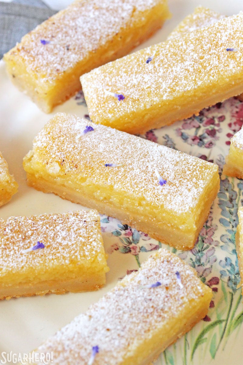 Lavender Lemon Bars - close-up of lemon bars with powdered sugar and lavender buds sprinkled on top | From SugarHero.com