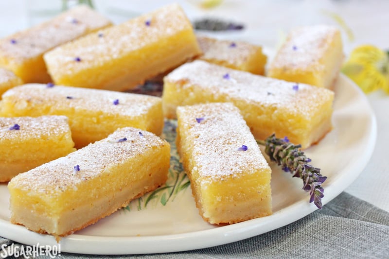 Lavender Lemon Bars - rectangular bars arranged on a plate | From SugarHero.com