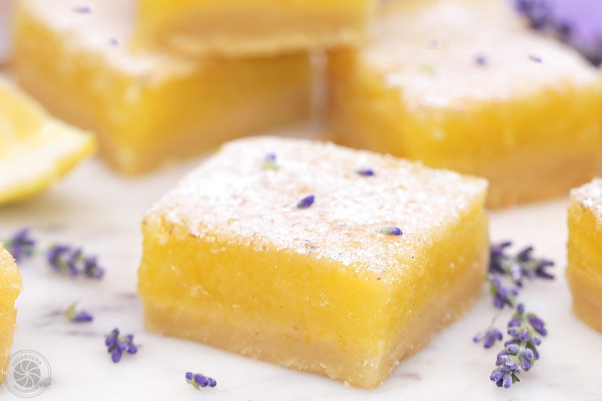 Lavender Lemon Bars - plate of lemon bars with powdered sugar sprinkled on top | From SugarHero.com