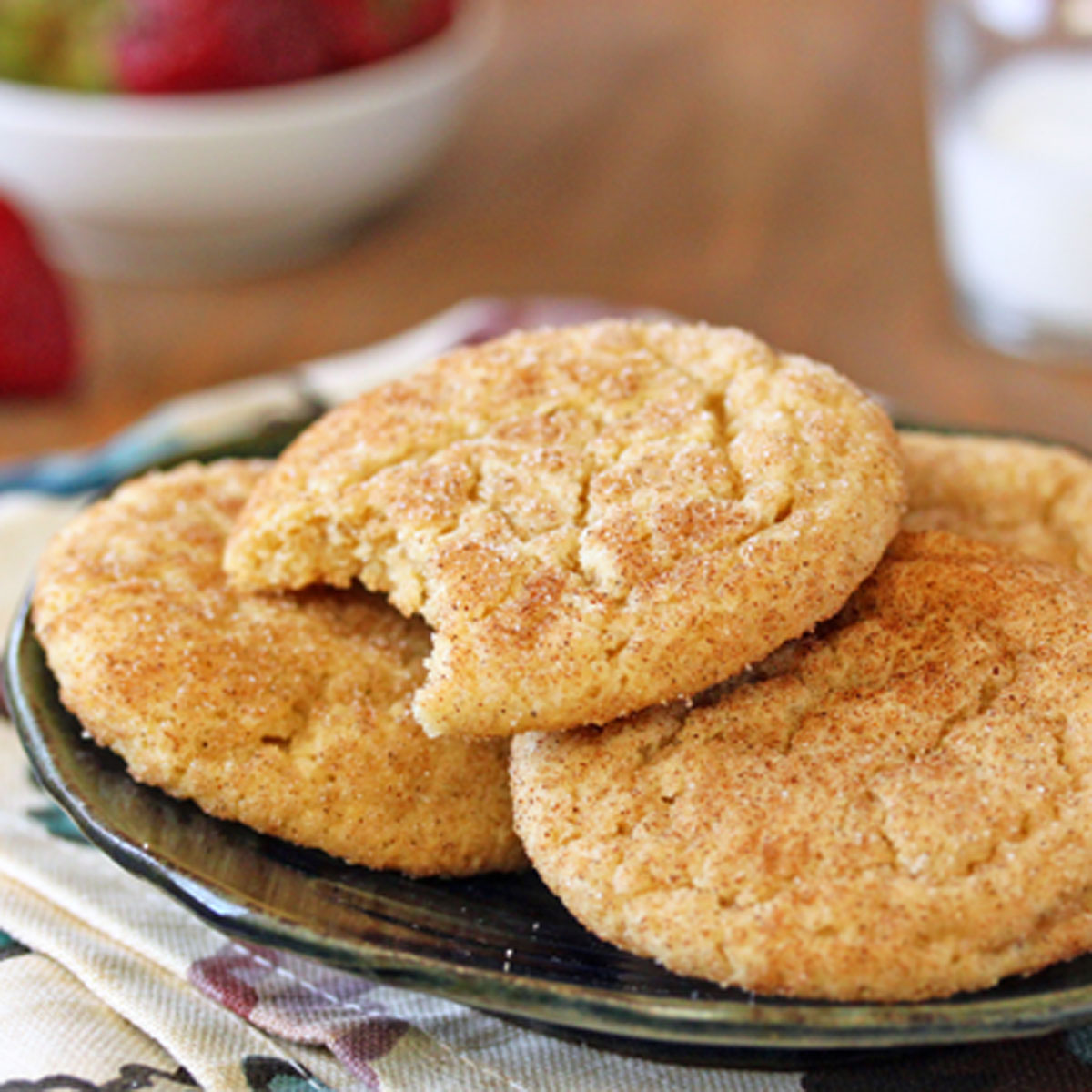3 Snickerdoodle Cookies on a plate with a bite removed from the top cookie.