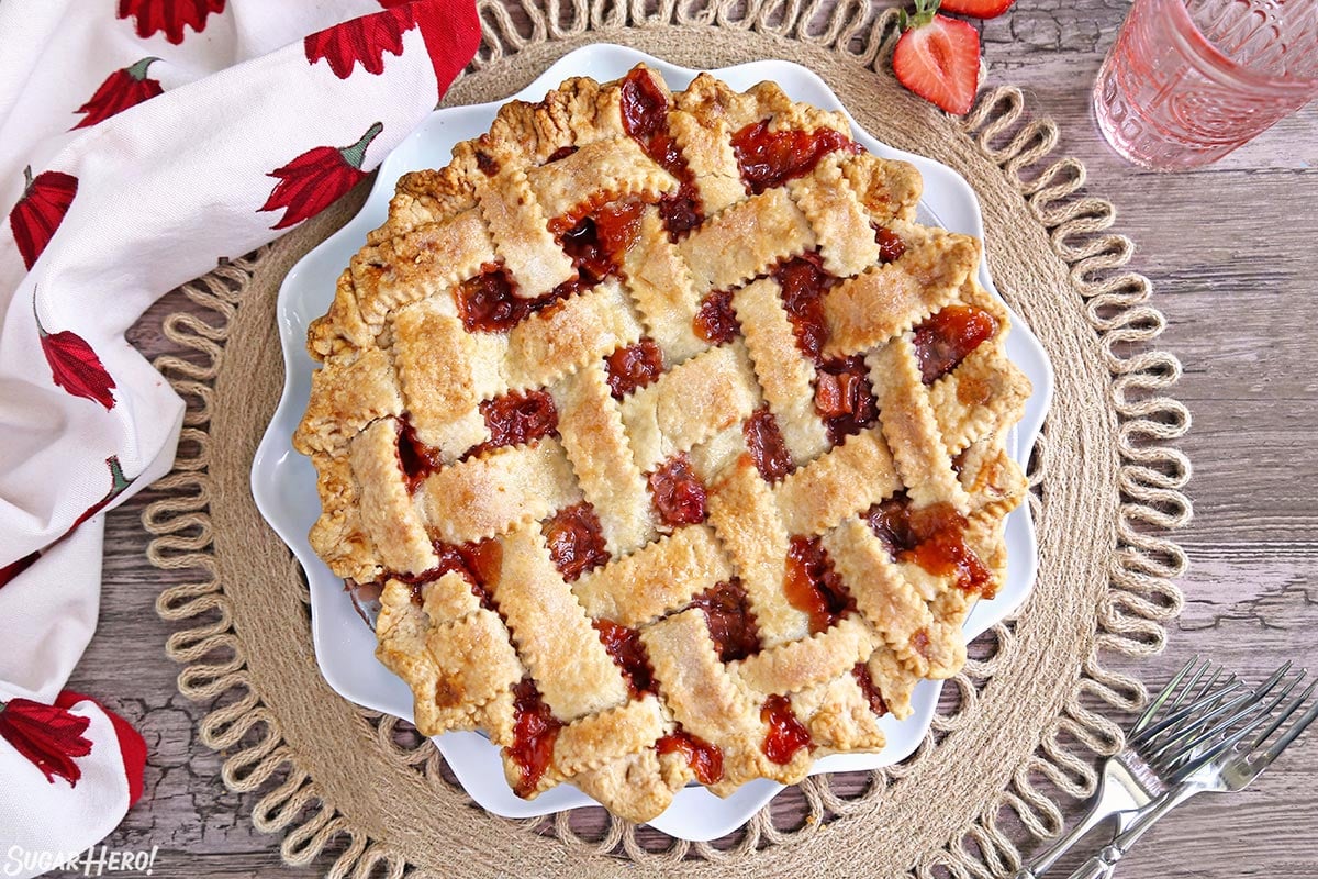 Strawberry Rhubarb Pie is a summertime classic! A flaky, buttery crust is filled with the perfect combination of sweet, juicy strawberries and tart rhubarb. | From SugarHero.com Strawberry Rhubarb Pie - lattice-topped pie on a serving plate | From SugarHero.com