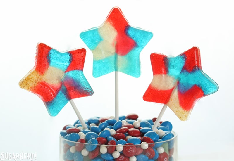 Easy Homemade Lollipops - three red, white, and blue translucent lollipops | From SugarHero.com