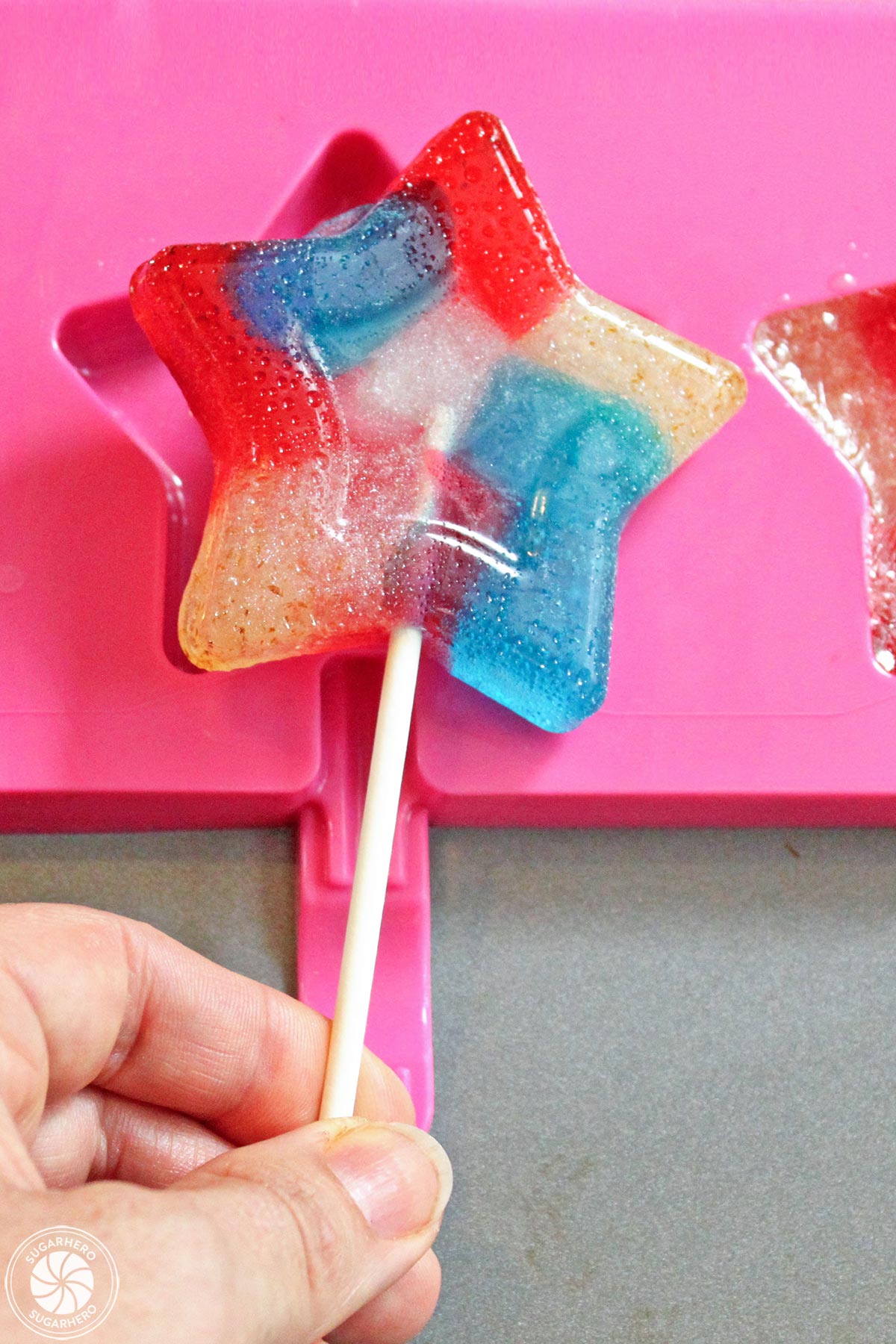 Easy Homemade Lollipops - removing red, white, and blue star-shaped lollipop from candy mold | From SugarHero.com